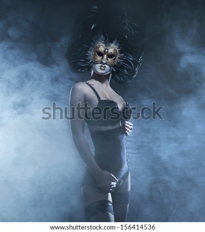 Sexy and bizarre woman in mask and lingerie over the smoky background