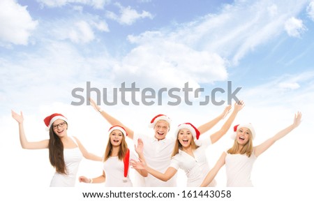 A group of happy and emotional teenagers in Christmas hats posing over heaven background