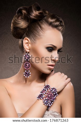 Young, Beautiful And Rich Woman In Jewels Of Gold And Stones Over Luxury Background