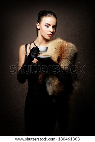 Young, rich and beautiful woman with the cup of coffee over the vintage background