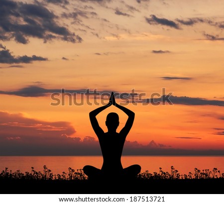 Sunset meditation. Silhouette of a woman doing yoga exercise in the evening.