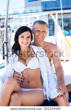 Handsome and rich man and a beautiful and sexy woman in swimsuit relaxing on a sailing boat