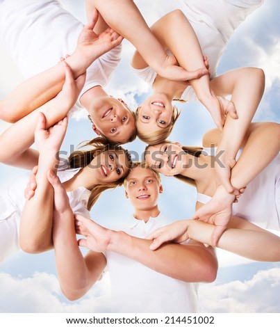 Large group of smiling teenage friends looking at camera over sky background