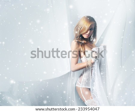 Young and sexy woman in white lingerie over a winter background with a snow