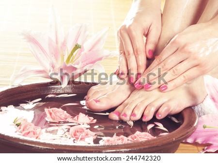 Legs, flowers, petals and ceramic bowl. Spa, recreation and skin care concept.