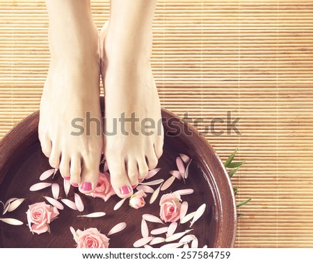 Legs, flowers, petals and ceramic bowl. Spa, recreation and skin care concept.