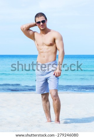Young, fit, muscled and handsome man on a summer beach