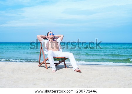 Young, fit and handsome man with athletic and muscled body chilling in a beach chair at summer