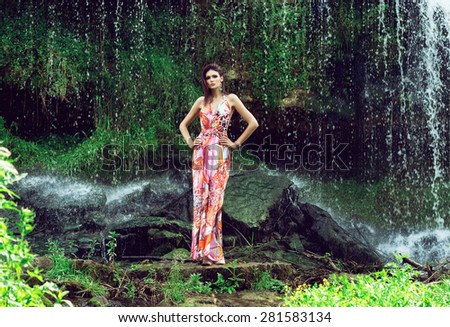 Beautiful fashion model posing in front of the waterfall