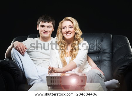 Young couple watching movie or sport broadcast on tv sitting on sofa in living room.