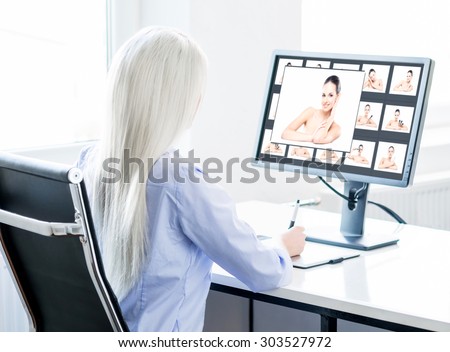 Young, attractive and confident woman working in office. Retoucher editing photos.