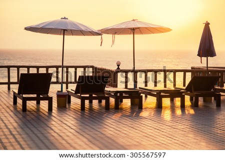 Terrace with a view on sea and sunset. Umbrellas and lounge chair in a sunlight.