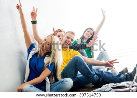 Group of happy students on a break waving. Focus on students. Background is blurry.