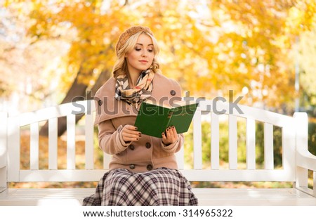 Sensual girl reading a poetry book in the park sitting on the bench.