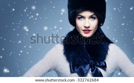 Fashion style portrait of a woman in an elegant winter fury clothes over snowy background.