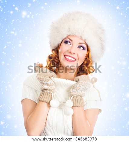 Young and beautiful woman in a winter dress over Christmas background with snow.