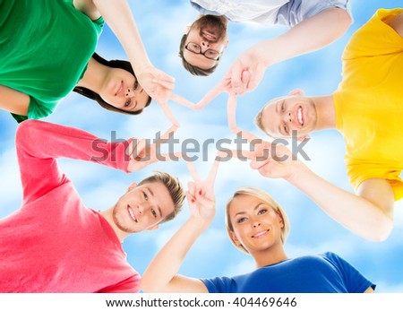 Happy students in colorful clothing standing together over blue sky background
