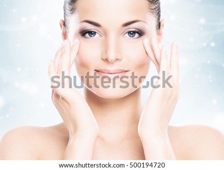 Face of attractive and healthy woman over seasonal Christmas background with a winter snowflakes. Healthcare, spa, makeup and face lifting concept.