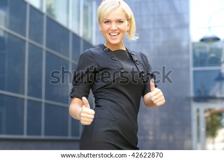 Young attractive business woman showing signs of success over modern background