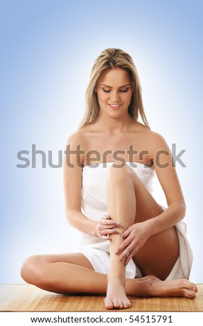 Young and beautiful blond in towel over blue background