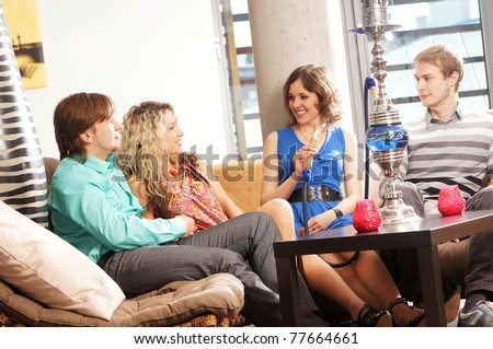 Group of young and sexy people smoking hookah in the lounge caffee