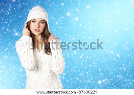 young pretty woman in winter dress over blue background with some snowflakes
