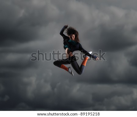 Young and sexy modern dancer over dramatic sky background