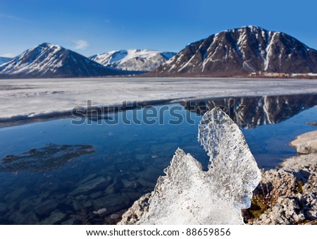 Big piece of ice on coast of lake in mountains