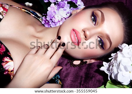 fashion studio photo of beautiful sensual woman with dark hair and bright makeup,with flowers