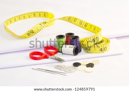 Set of tailor\'s tools, Set for sewing - scissors, spool of thread, needle, thimble, etc. on white fabric.