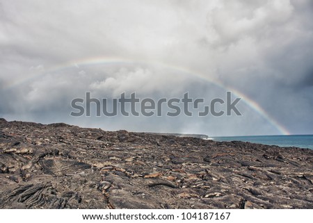 rainbow over lava flow from erupting volcano in Hawaii