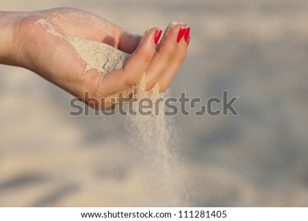 Single woman hand with sand and red nails