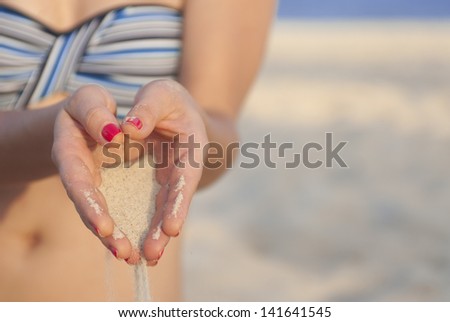 Two hands with sand and red nails om the beach