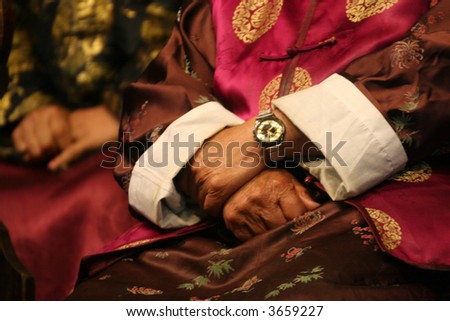 chinese old man who in traditional clothes crossing his hands