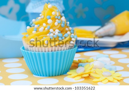 Blue and yellow cupcake with tip and whipped cream