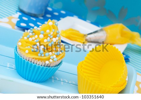Blue and yellow cupcake on a plateau with empty cups