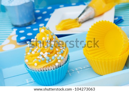 Blue and yellow cupcake setting with whipped cream