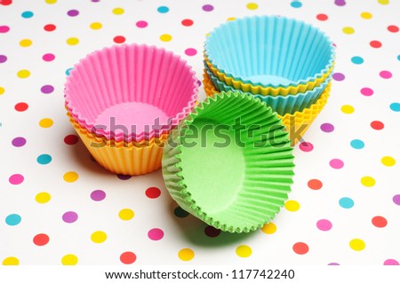 empty cupcake cases on a colorful dotted background