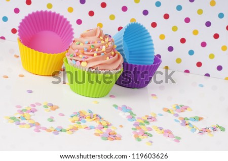 cupcake and empty cups with the word cake in sprinkles