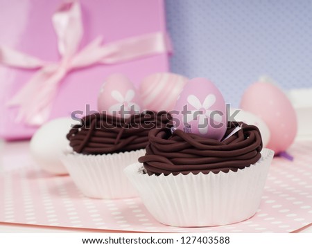 pastel Easter decoration cupcakes with pink present in the background