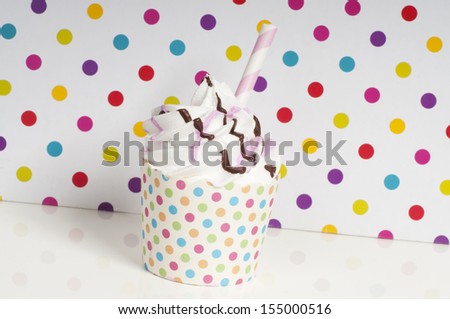 Cupcake with whipped cream on a rainbow dotted background