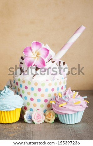 Cupcake with mini cupcakes and chocolate straw on a brown background