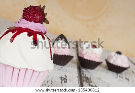 Strawberry cupcake with three baby chocolate cupcakes in the background