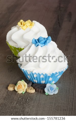 blue and yellow cupcake with whipped cream on a wooden table