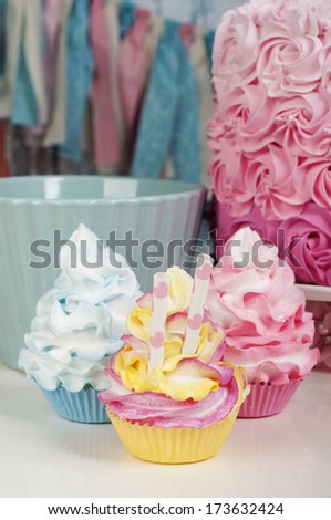 three cupcakes in pink, blue and yellow
