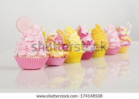 Loads of pink and yellow cupcakes on a white background