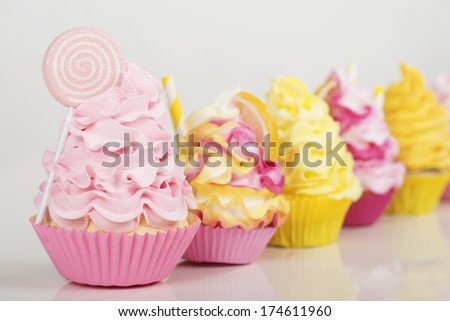 a row of pink and yellow cupcakes on a white background