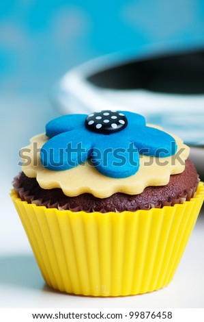 chocolate cupcake with yellow and aqua blue flower on top