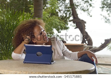 Young brunette curl hair with pensive pose in front of a digital table