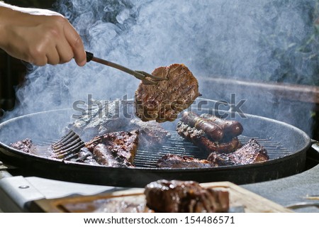 Man doing a barbecue, steak, sausage, lamb, pork